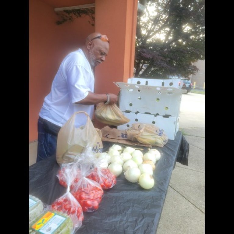 Volunteer placing vegetables on table outdooors